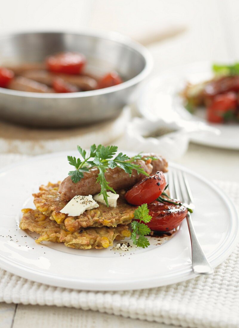 Mais-Süsskartoffel-Puffer mit Bratwürstchen und Tomaten