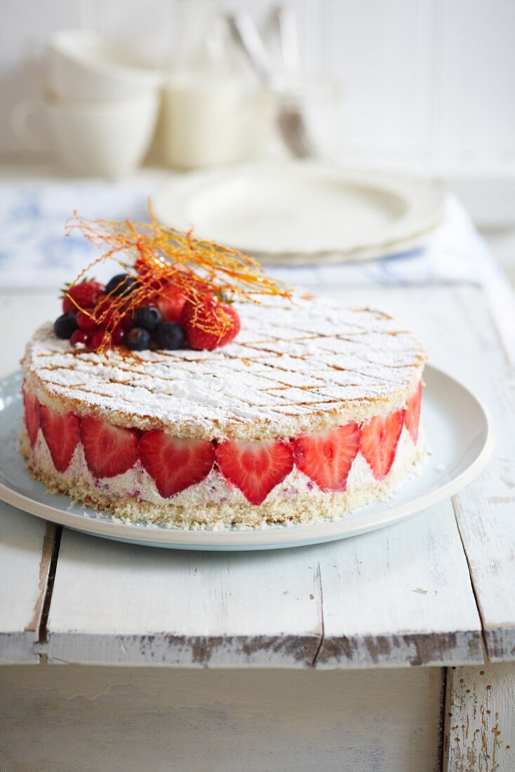 Strawberry fridge cake with mixed berries and caramel threads