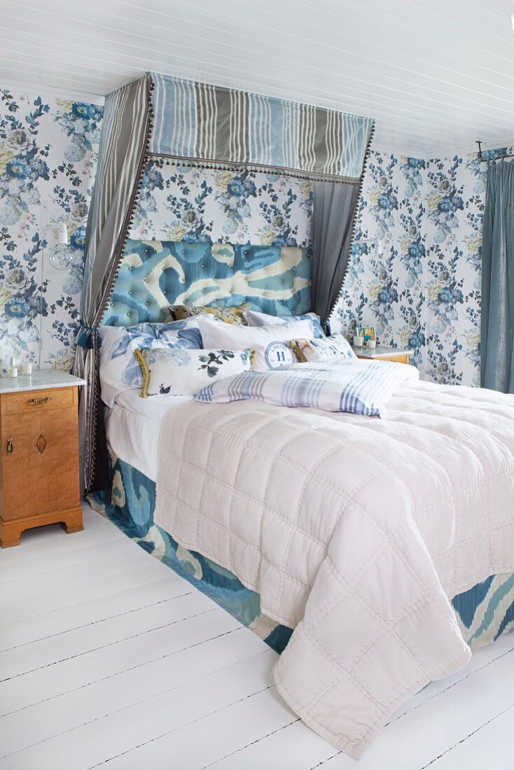 Doppelbett mit gestreiftem Baldachin am Kopfende in romantischem Schlafzimmer mit blauer floraler Tapete