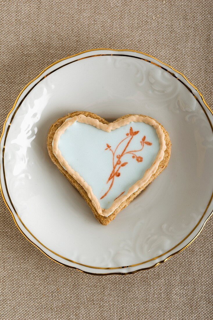 A heart-shaped biscuit with an egg white glaze and a stamped motif