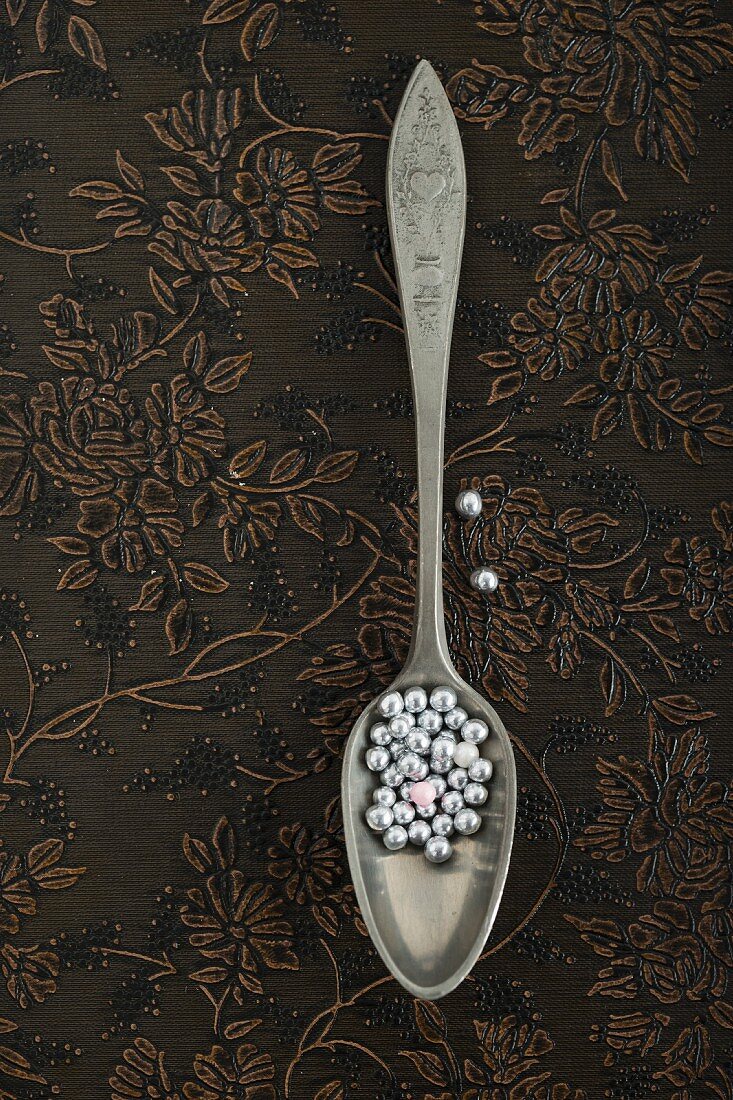 Silver sugar pearls on a spoon