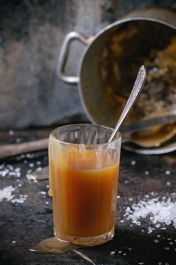 Selbstgemachte Karamellsauce im Glas vor altem Kochtopf