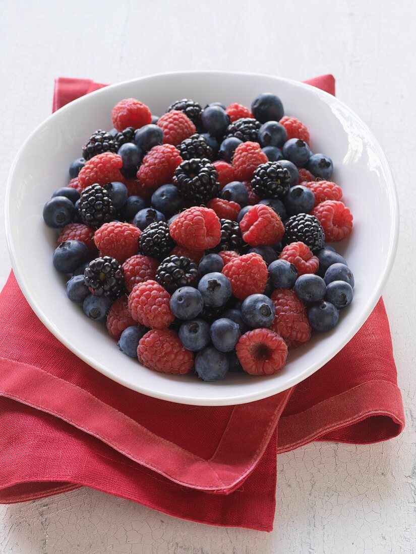 Various fresh berries in a bowl on a tea towel