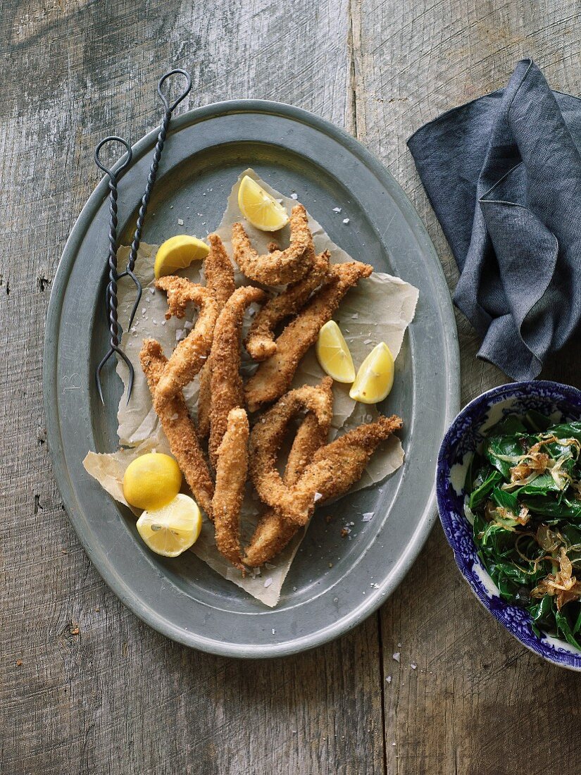 Deep-fried fish with lemon wedges and green cabbage