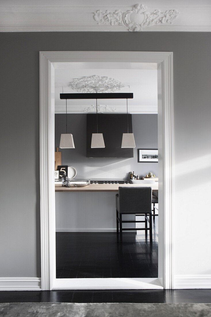 Blick von elegantem Vorraum mit Stuckfries durch Türöffnung auf Kücheninsel
