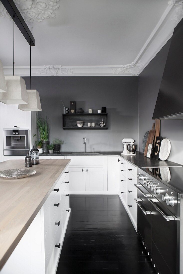 Island counter with wooden worksurface and L-shaped kitchen counter against grey-painted wall in traditional interior