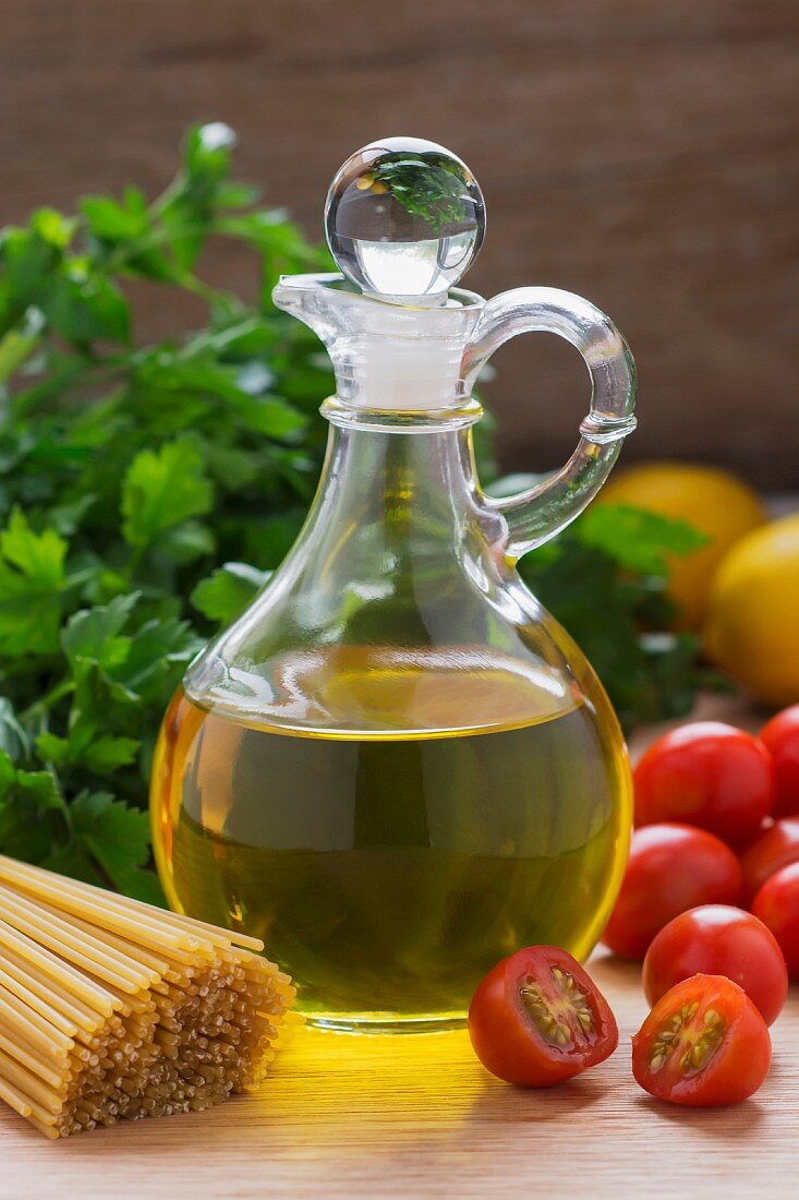 Olivenöl, Tomaten, Petersilie und Spaghetti auf Holztisch