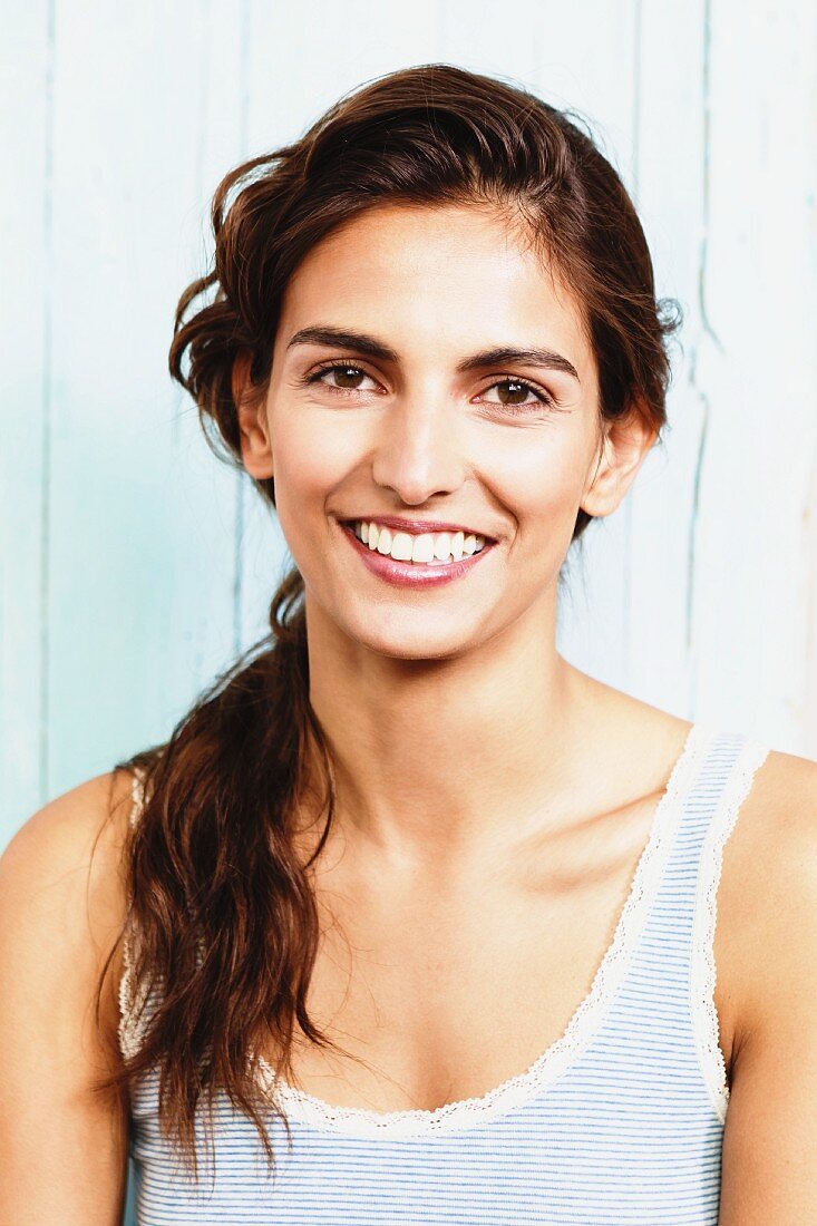 A young brunette woman wearing a striped vest with a lace trim