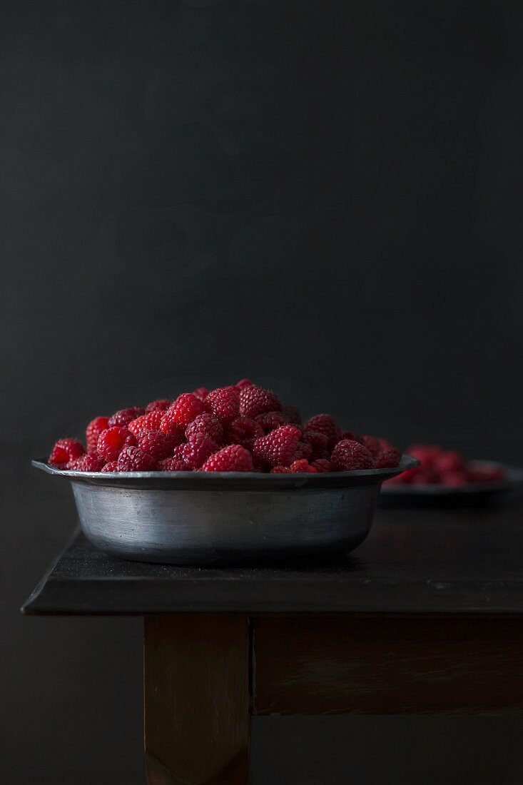 Frische Bio-Himbeeren in einer Metallschale auf Holztisch