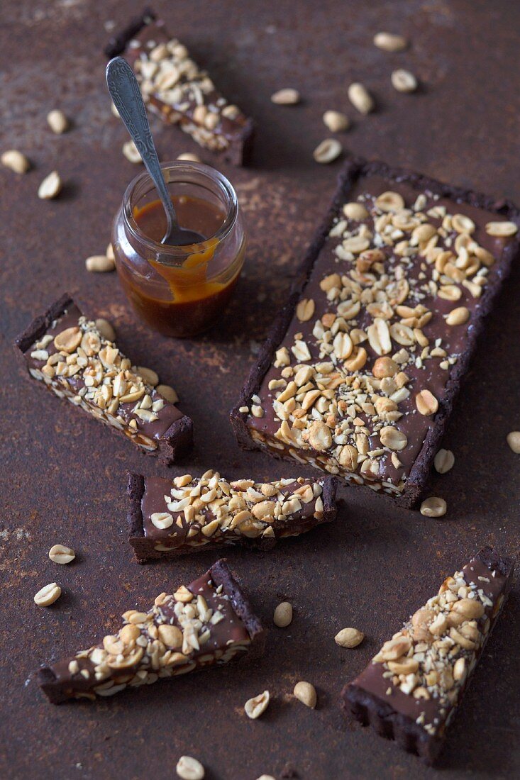 Slices of chocolate tart with peanuts and homemade caramel sauce