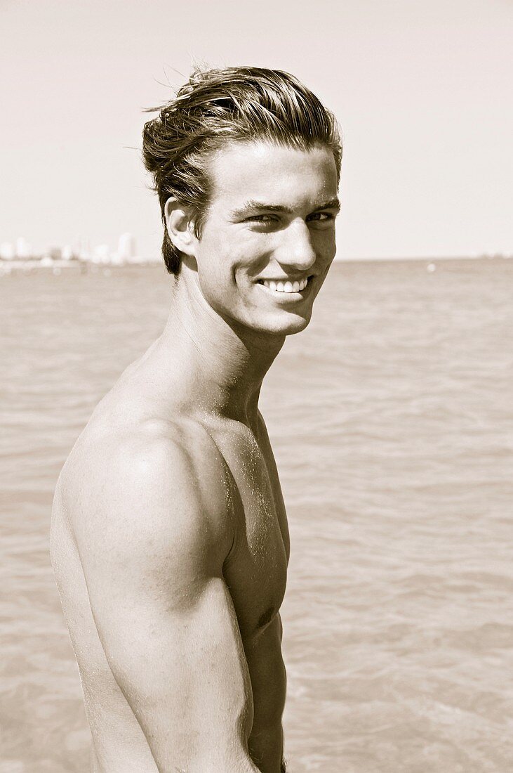 A muscular young man by the sea (black-and-white shot)