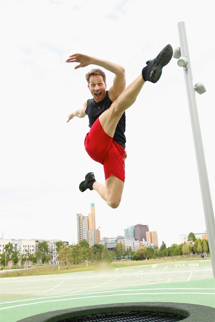 A man trampolining in a park against a skyline