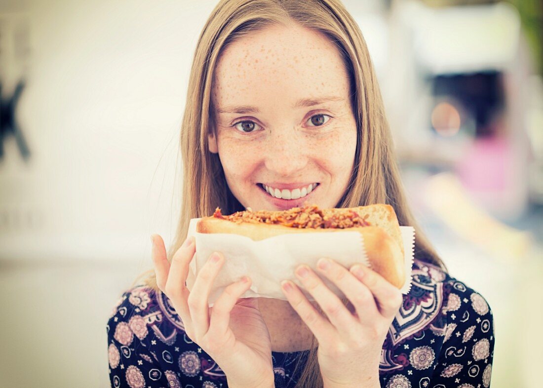 A young woman with a pulled pork sandwich