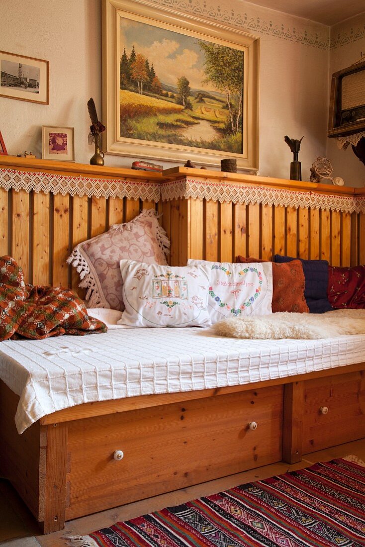 Fitted wooden bench with drawers and embroidered cushions in corner of rustic dining room