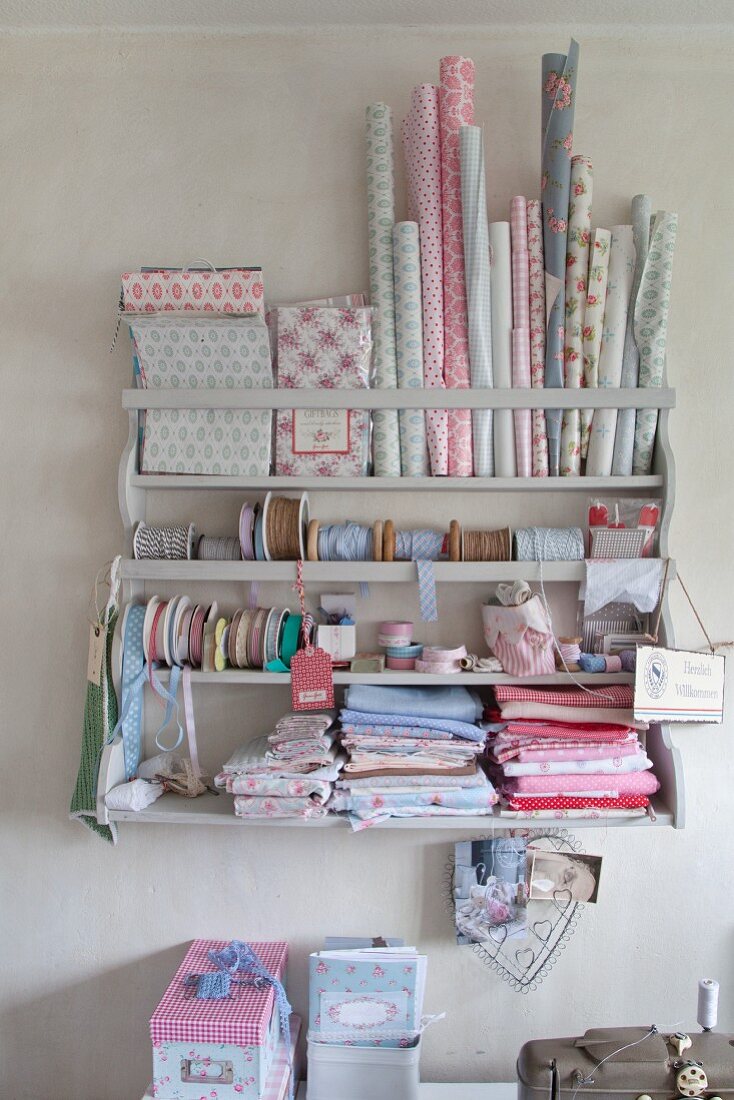 Collection of patterned pastel fabrics and trims on old wall-mounted shelving