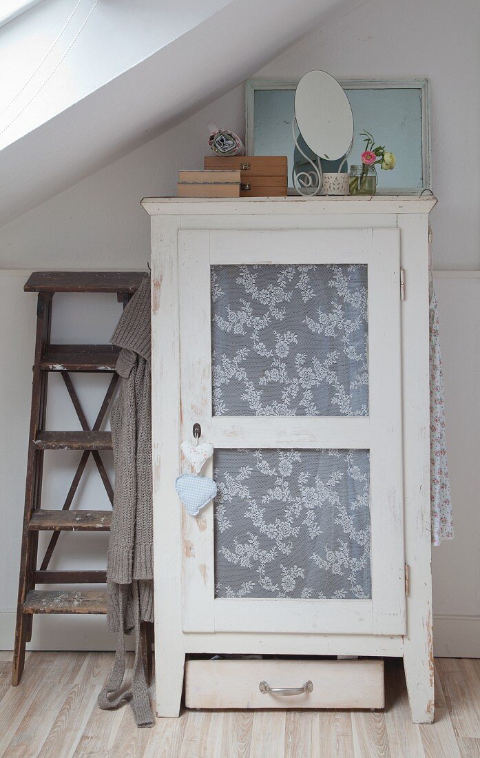 Shabby-chic cupboard with lace fabric in panelled door