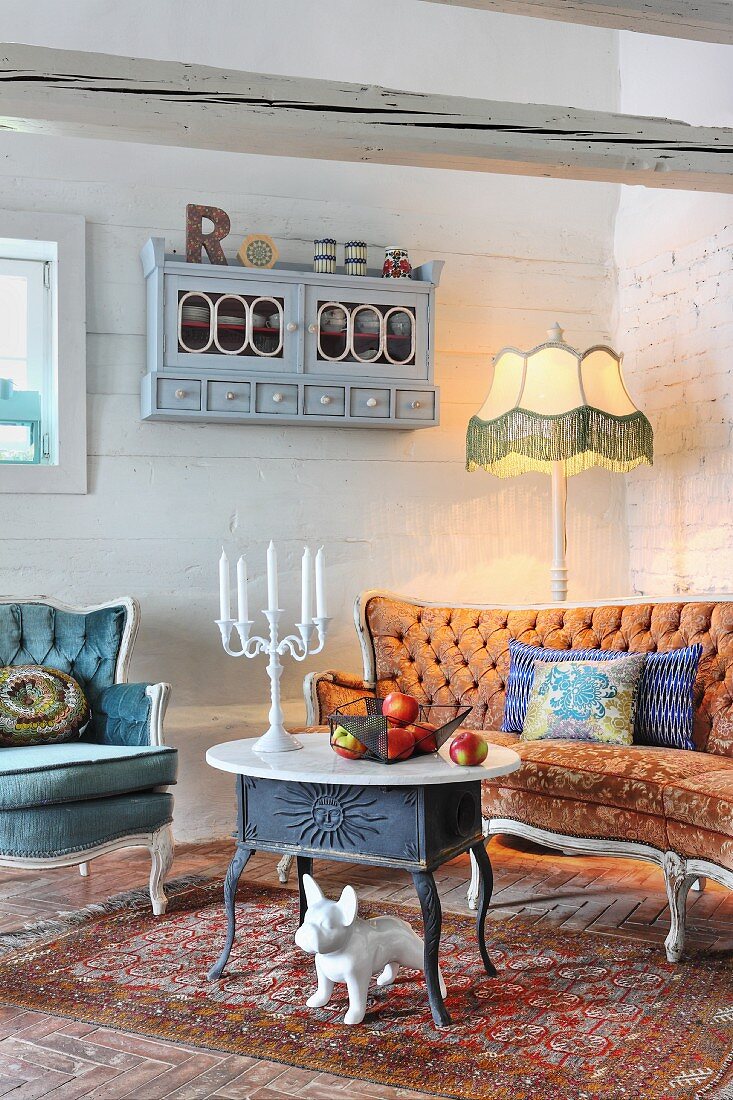 China dog under cast iron table with marble top in front of antique couch and traditional standard lamp in corner of rustic interior