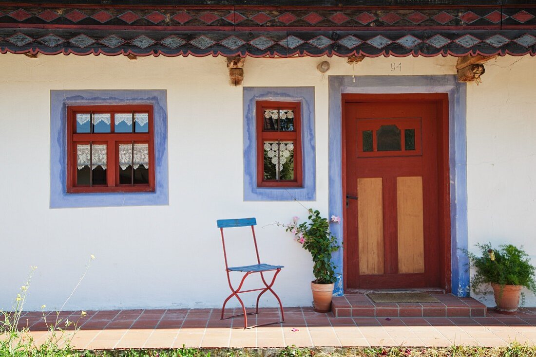 Detail of old renovated farmhouse with blue trims around red windows and door