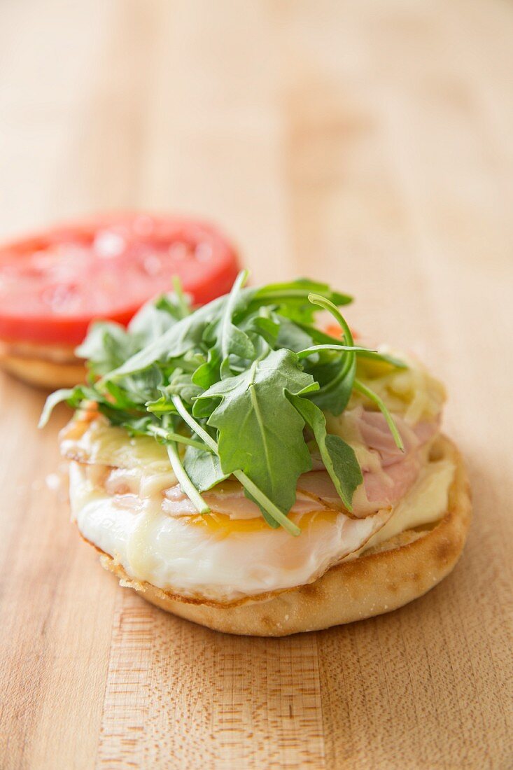 An English muffin with eggs, cheese, ham rocket and tomatoes for breakfast