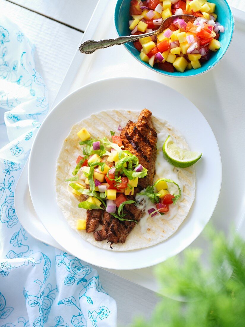 A taco with grilled Creole fish and a mixed salad with mango