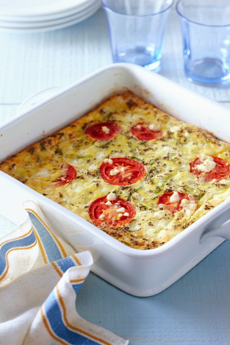 Oven-baked frittata with tomatoes, cheese, spring onions and herbs