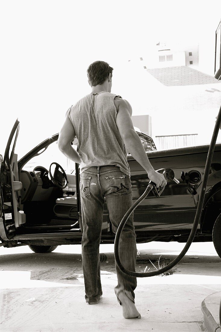 A sporty young man filling up a car