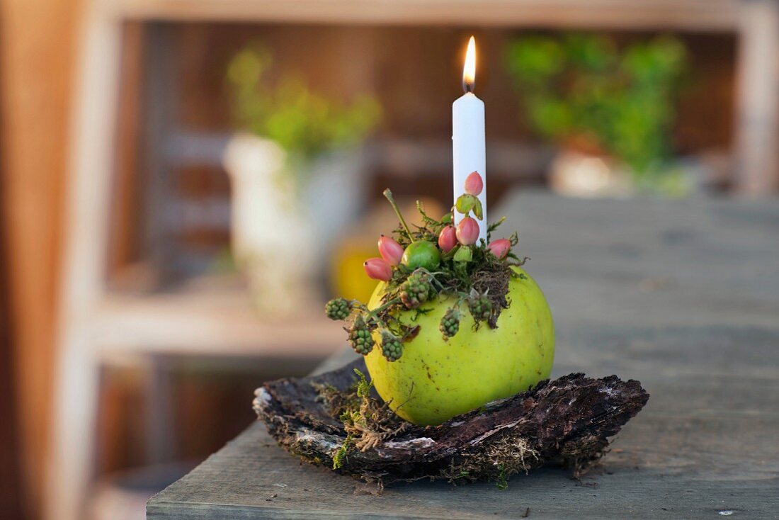 Lit candle stuck in decorated apple