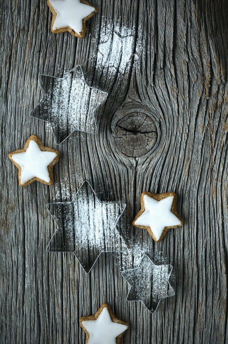 Ausstechförmchen-Sterne mit Puderzucker und Zimtsterne auf Holzbrett