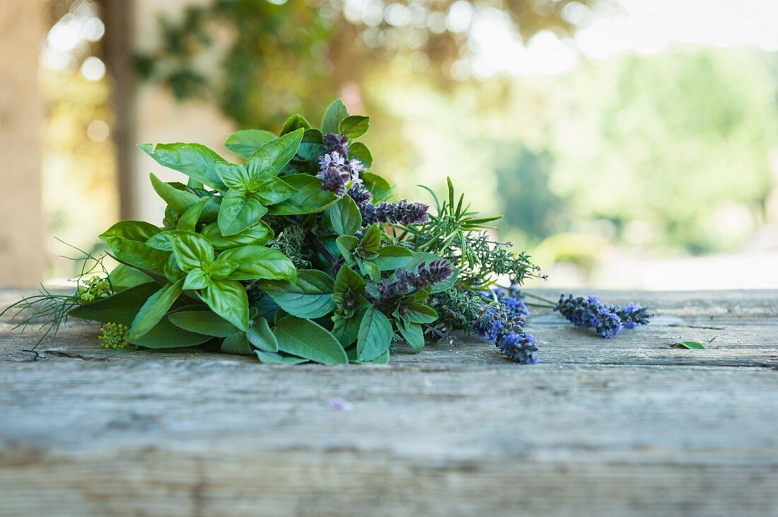 A bunch of fresh herbs with lavender flowers on a wooden table