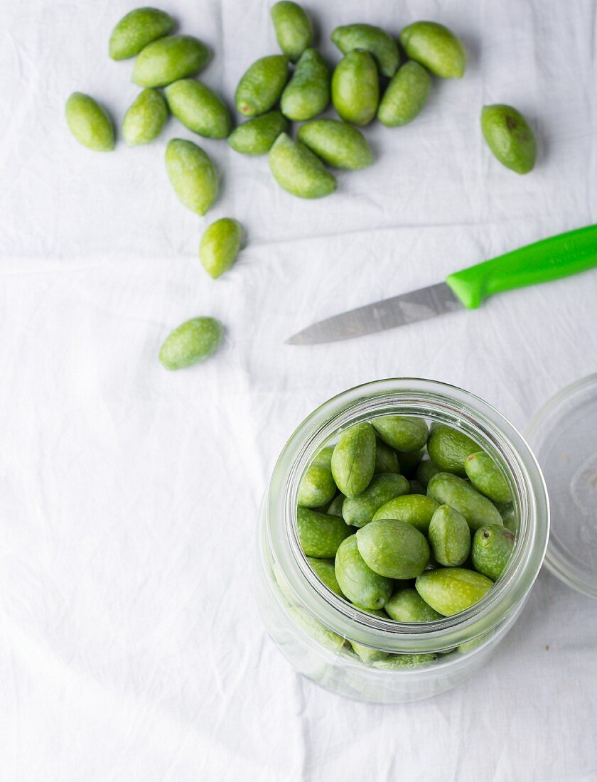 Fresh olives, some in a preserving jar