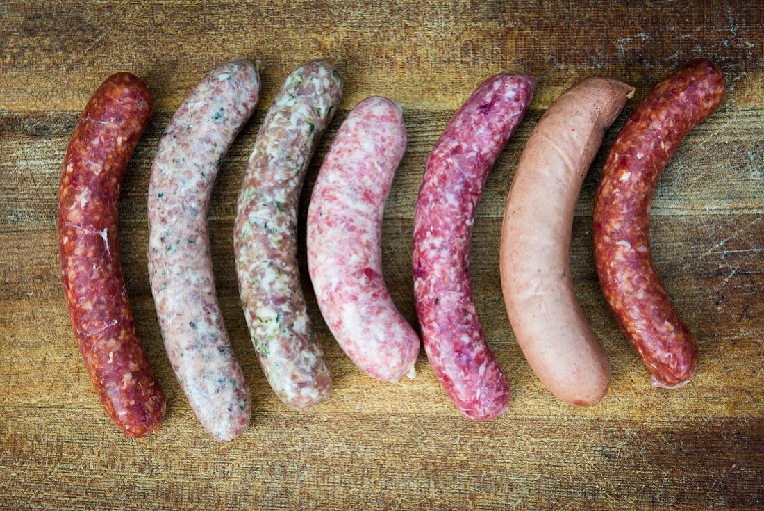 Various fresh sausages on a wooden surface