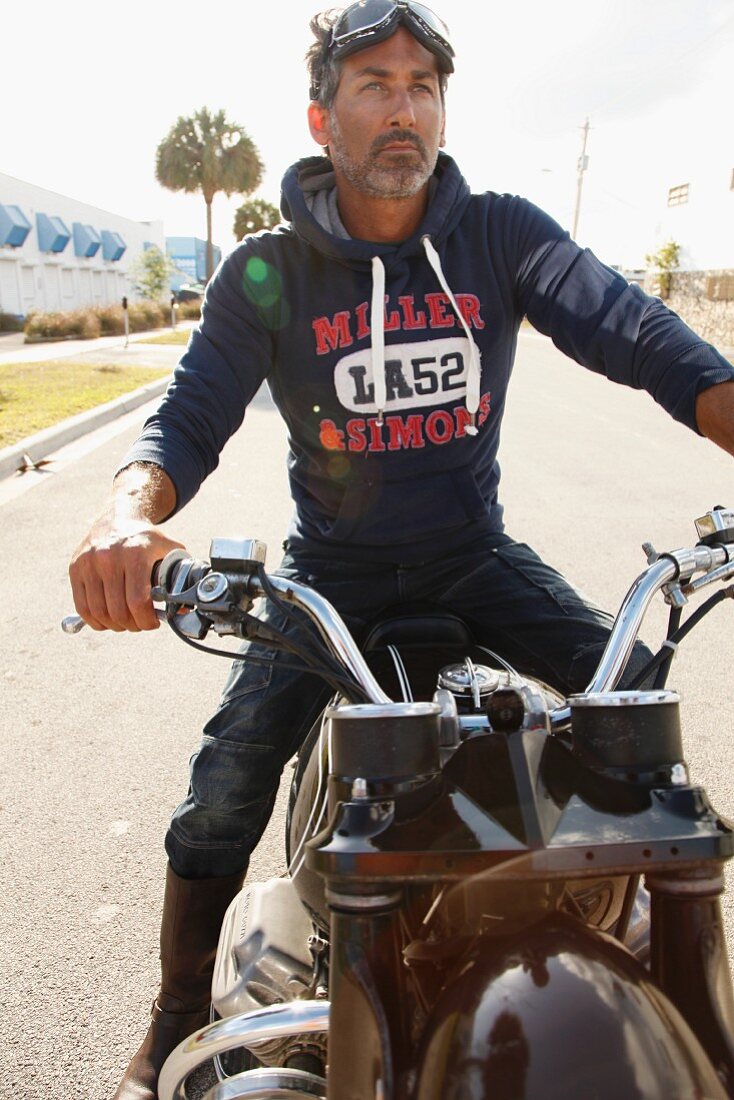 Mann mit Kapuzensweater sitzt auf Motorrad