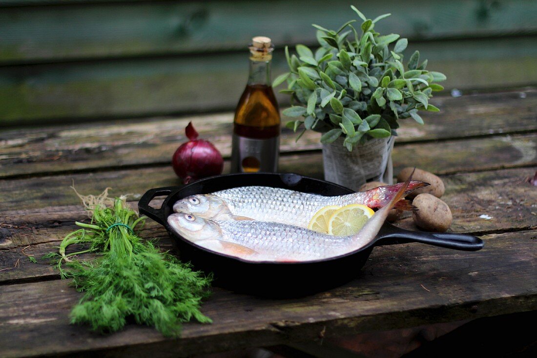 Fresh fish, herbs, vegetables and balsamic vinegar on a wooden table