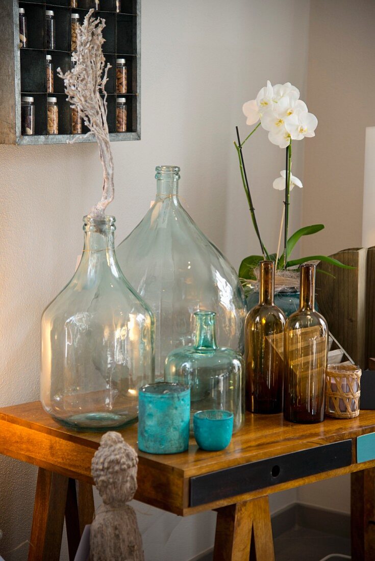 Verschiedene Glasflaschen und Orchidee auf Schreibtisch