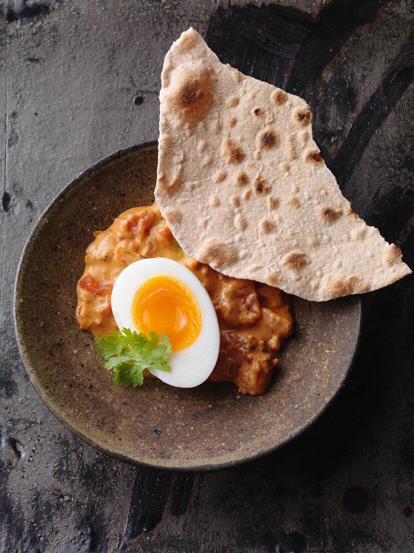 Vegetarian egg curry with garam masala and tomatoes served with chapatisis