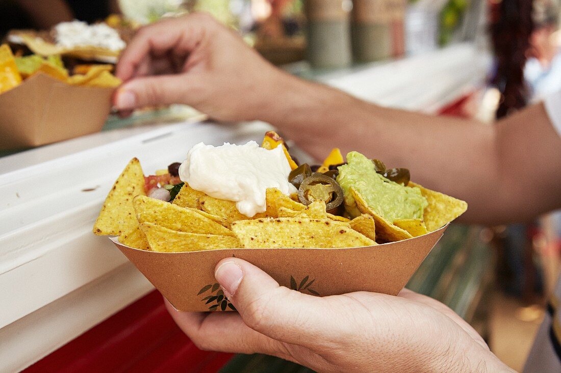 Tortillachips mit Sauerrahm und Guacamole auf dem Markt (Barcelona, Spanien)