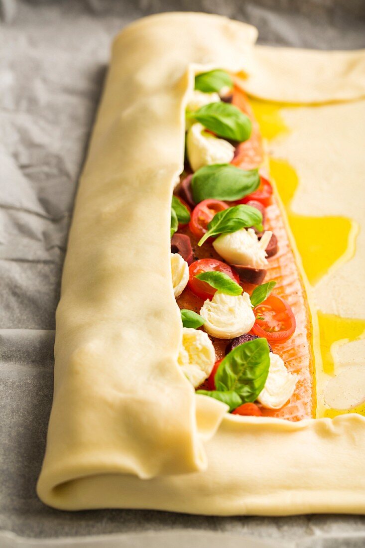 Alpine salmon with tomatoes, mozzarella and basil being wrapped in puff pastry