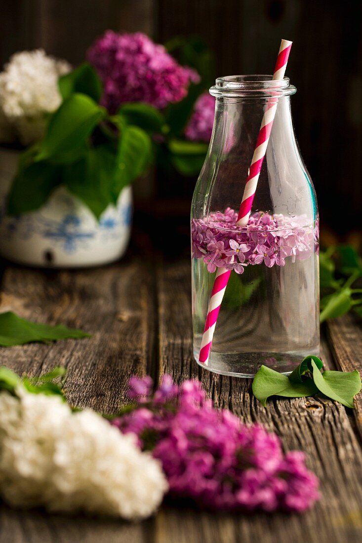 Lilac flower water in a bottle with a straw
