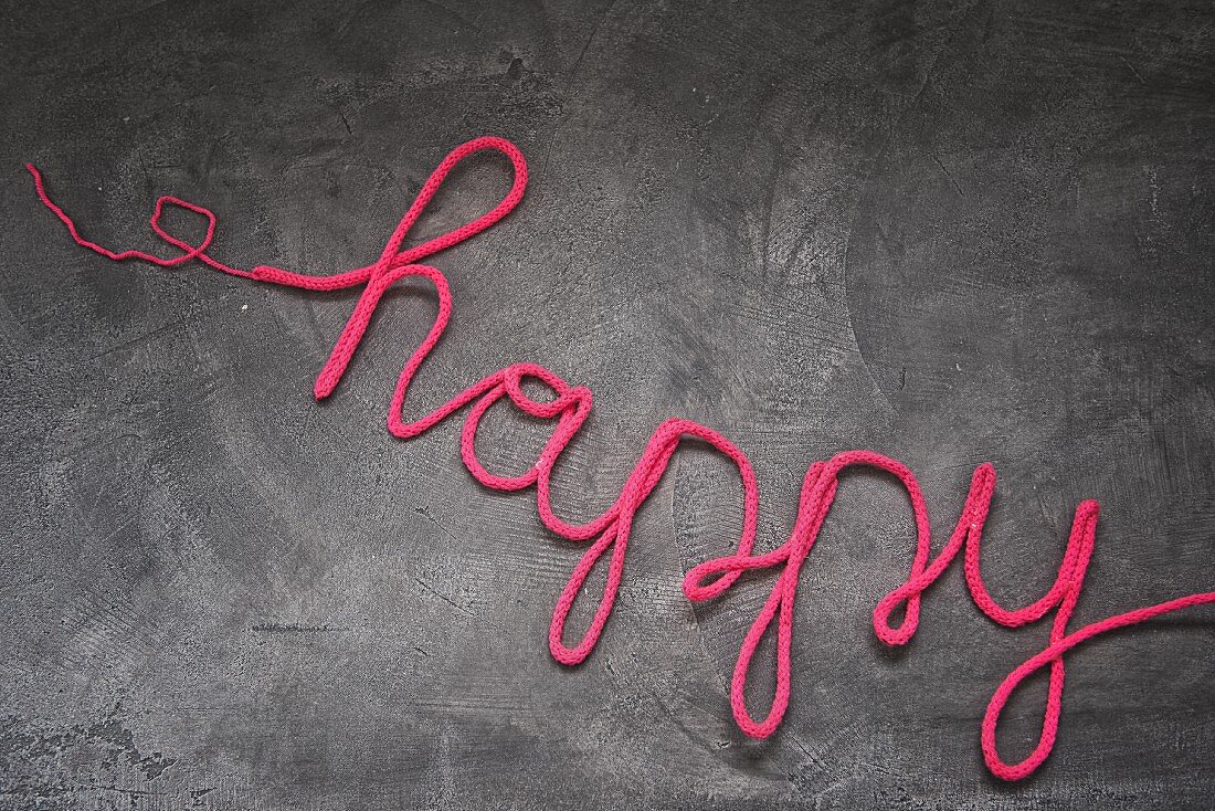 Wire covered in pink wool bent to spell 'happy'