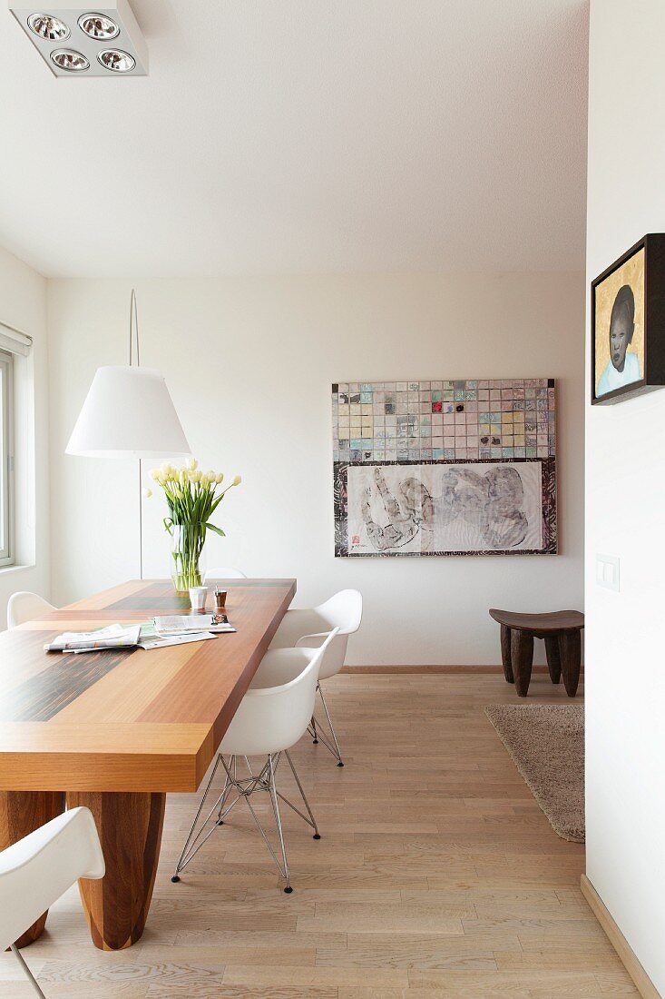 Solid wood dining table, delicate classic chairs with white shell seats and African wooden stool in modern interior