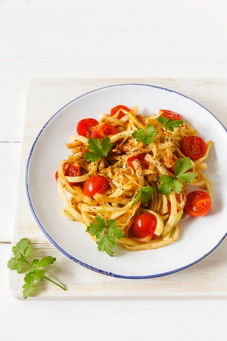 Vegetable spaghetti made from kohlrabi with steamed cherry tomatoes and garlic