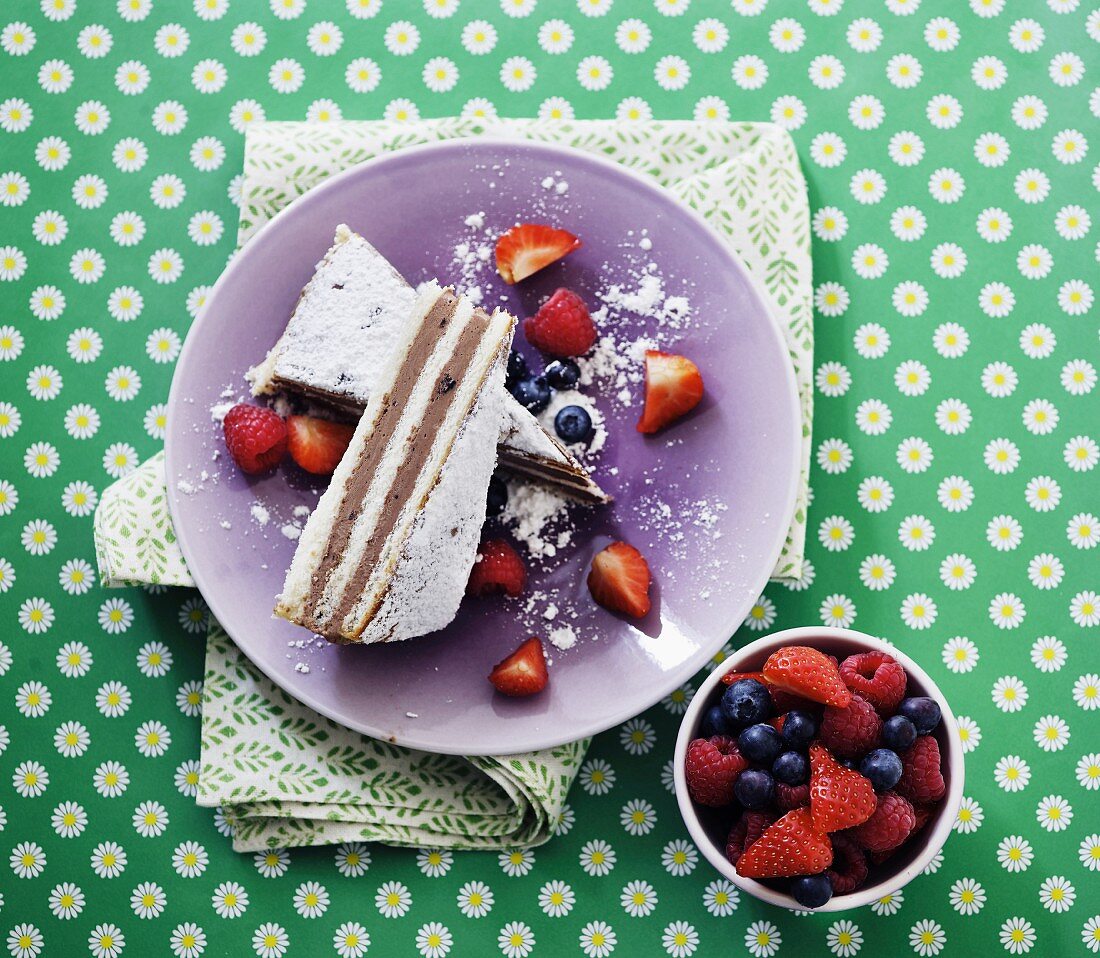 Zwei Stücke Schichttorte mit Beeren und Puderzucker