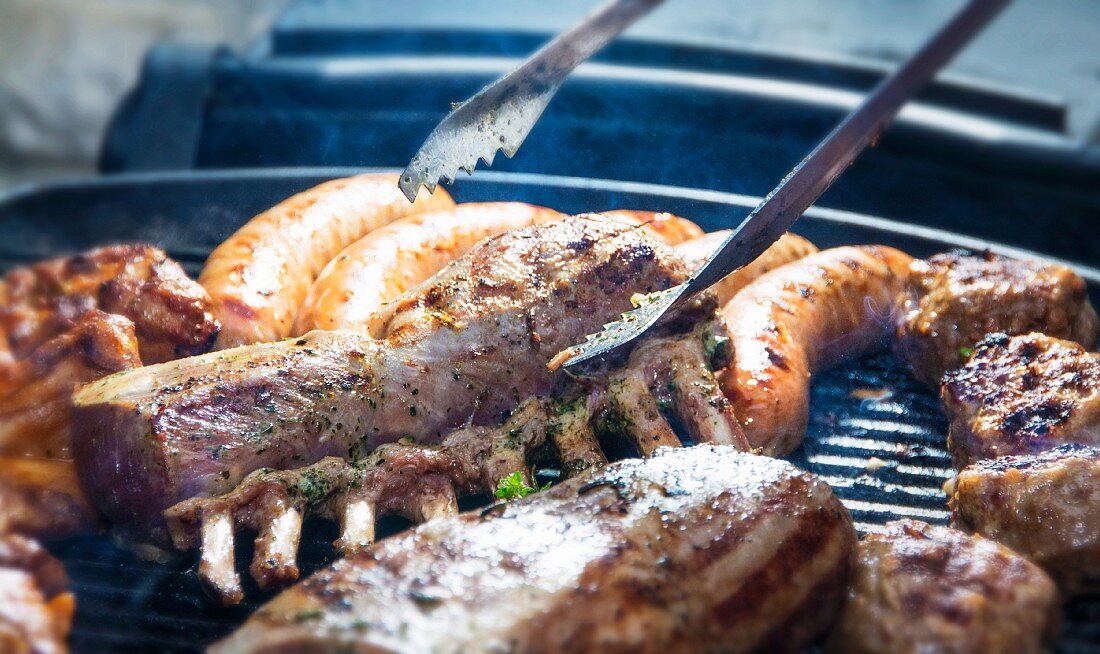 Meat, sausage and a rack of lamb on a barbecue