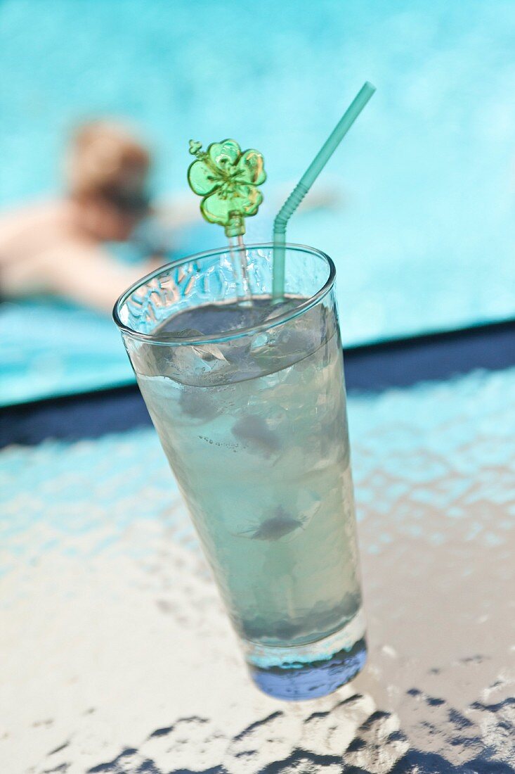 A lime drink with ice cubes by a pool