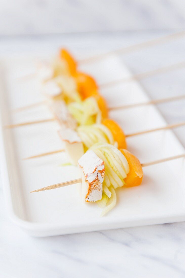 Skewers with rolled courgette ribbons, peaches and cheese on a serving platter
