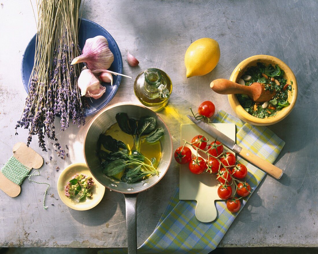 Stillleben mit Kräutern, Knoblauch, Olivenöl, Zitrone und Kirschtomaten