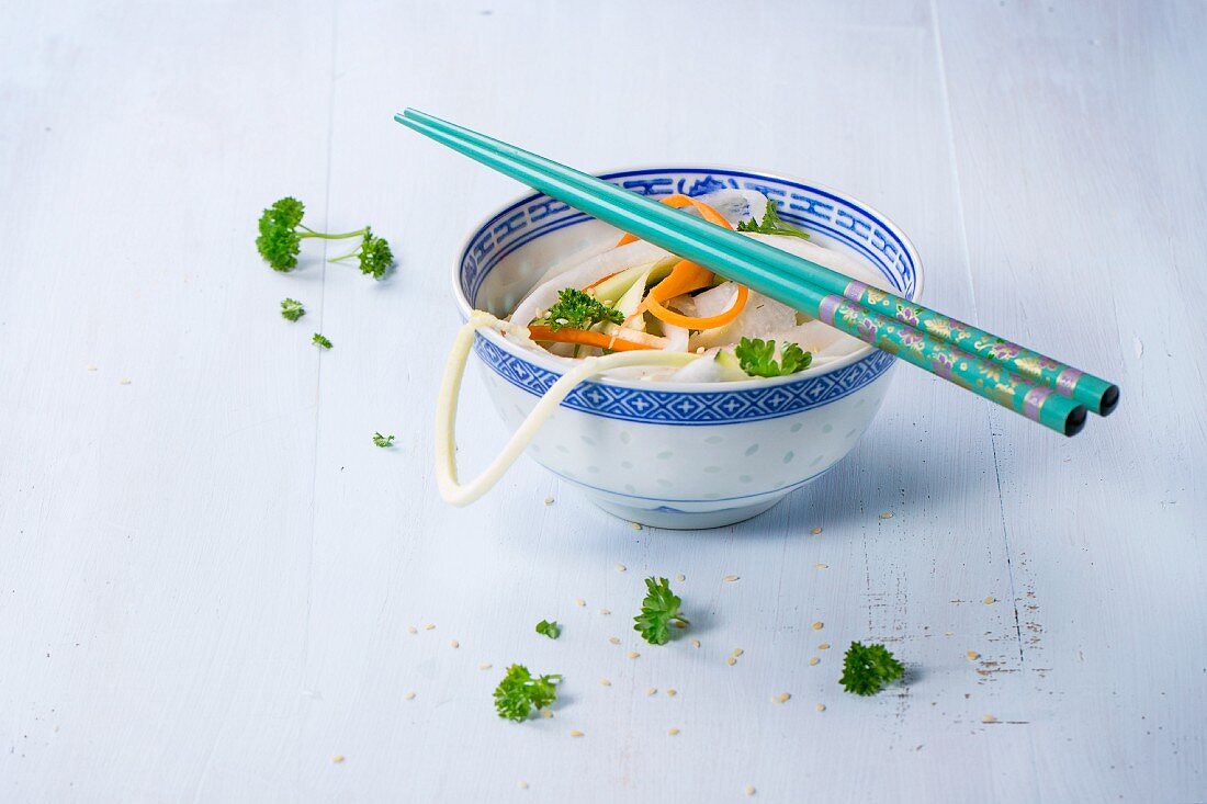 Vegetable noodles with parsley and sesame seeds in an oriental bowl with chopsticks