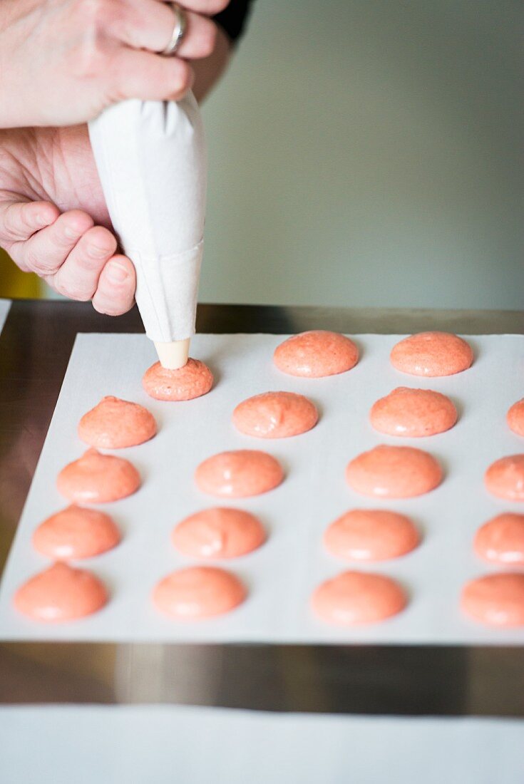 Rosafarbene Macarons auf Backpapier spritzen