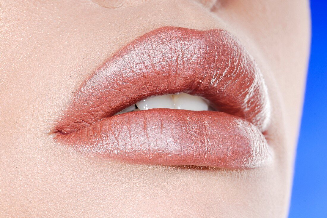 A woman's lips with pink-brown lipstick, close-up