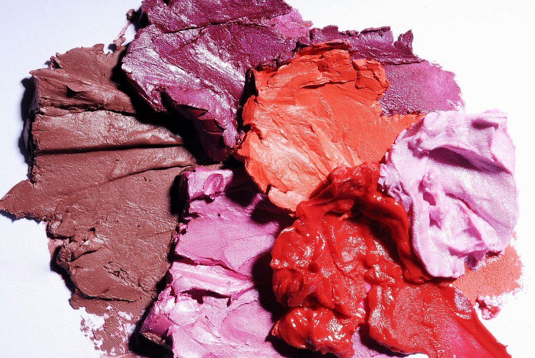 Lippenstifte in Rosé- und Rottönen verstrichen auf weißem Untergrund